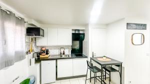a kitchen with white cabinets and a small table at La Parenthèse Urbaine - T2 Cosy et fonctionnel - Metro 5 Bobigny in Bobigny