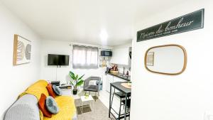 a living room with a yellow couch and a kitchen at La Parenthèse Urbaine - T2 Cosy et fonctionnel - Metro 5 Bobigny in Bobigny