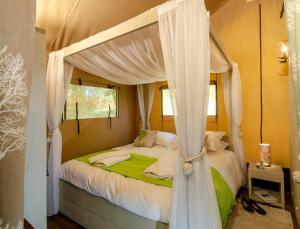a bedroom with a canopy bed with white curtains at Blencathra - Safari Tent in Ambleside