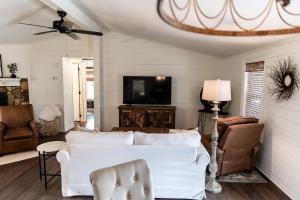 a living room with a white couch and a tv at The Cottage at Cardinal Hill in Dahlonega