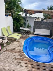 a blue pool on a wooden deck with chairs and a table at villa des Filaos et du lagon 0693-70'59'79 in Saint-Leu