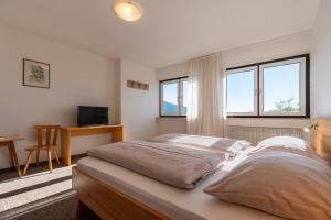 a bedroom with a large bed and two windows at Pension Rastnerhof in Luson +22 photos