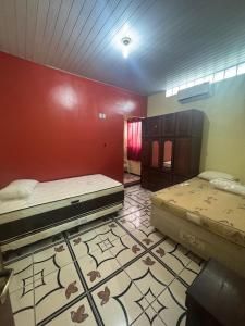 a room with two beds and a red wall at Casa Altos JM in Ananindeua