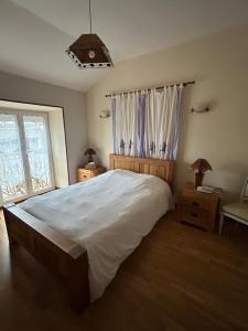 a bedroom with a large white bed and a window at La Ferme de Francois in Saudron