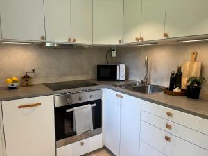 a kitchen with white cabinets and a stove and a microwave at Cozy guesthouse in Vallda in Vallda +13 photos