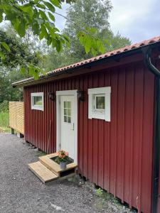 a red shed with a white door and a porch at Cozy guesthouse in Vallda in Vallda