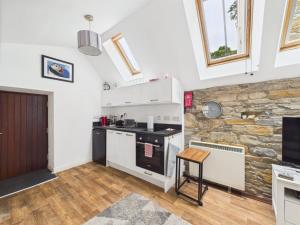 a kitchen with white cabinets and a stone wall at 52a Albert Street in Kirkwall +3 photos