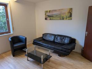 a living room with a black couch and a chair at Weinbergnest in Bad Dürkheim
