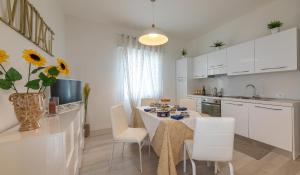 a kitchen with a table with white chairs and a kitchen with white cabinets at Lizard Residence in Lido di Jesolo