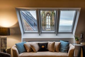 a couch in a living room with three windows at Arran Shores Luxury Shorefront Penthouse Suite 10 in Lamlash