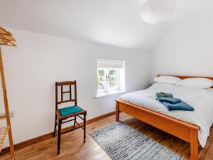 a bedroom with a bed and a chair at The Pink Cottage in Bottisham +9 photos