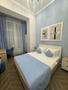 a bedroom with a large bed with blue sheets at Five Hotel in Astana