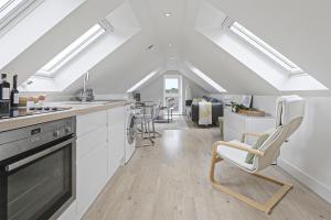 a kitchen with white cabinets and chairs in a room at The Loft modern flat in the heart of Wadebridge in Wadebridge