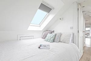 a white bedroom with a bed with a book on it at The Loft modern flat in the heart of Wadebridge in Wadebridge