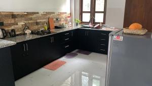 a kitchen with black cabinets and a white floor at Liya Villa in Ahangama