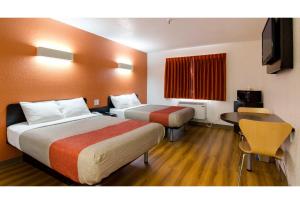 a hotel room with two beds and a table at Motel 6 Kerrobert, SK in Kerrobert