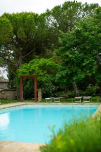 a swimming pool with benches in a park with trees at Fattoria San Donato in San Gimignano