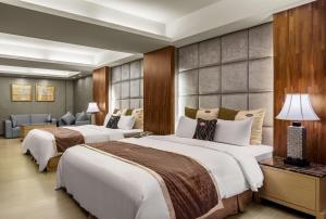 una camera d'albergo con due letti e un divano di Chuang-Tang Spring SPA Hotel - Deyang a Jiaoxi