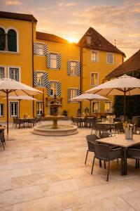 a patio with tables and umbrellas in front of a building at Georgi Schloss - Boutique Hotel in Ehrenhausen