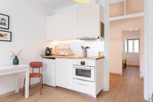 a kitchen with white cabinets and a table and a chair at Severa Apartments in Lisbon