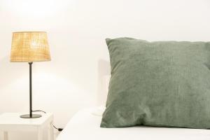 a green pillow sitting on a bed next to a lamp at Severa Apartments in Lisbon