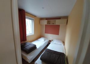 a small room with two beds and a window at location mobile home proche de la mer in Hermanville-sur-Mer
