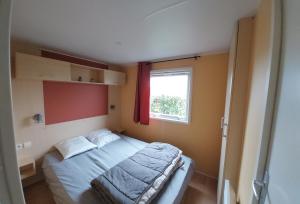 a small bedroom with a bed and a window at location mobile home proche de la mer in Hermanville-sur-Mer