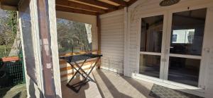 a screened porch with a table on the side of a house at location mobile home proche de la mer in Hermanville-sur-Mer