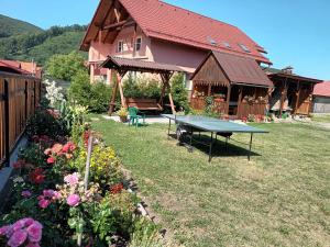 a picnic table in the yard of a house with flowers at Enikő vendegház in Praid +17 photos
