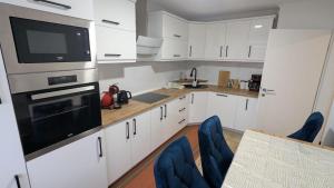 a kitchen with white cabinets and blue chairs at Heideperle, Ferienhaus in Schneverdingen