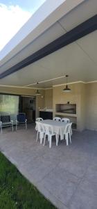 a group of white tables and chairs on a patio at The Yerbal Thermal House in Termas de Guaviyú