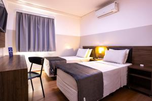 a hotel room with two beds and a table at Travel Inn Express Hotels Brás in São Paulo