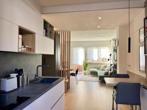 a kitchen with a sink and a living room at The Cozy Peak - 360 Dolomites View in Agordo
