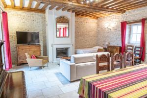 a living room with a couch and a television at La Ferme de la Gronde in Magny-en-Bessin