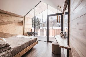a bedroom with a bed and a large window at Borgo Antico Mountain Lodge in Sappada
