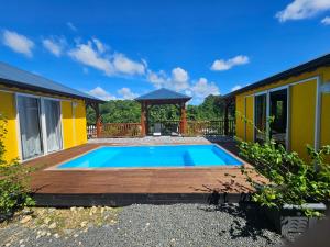 a swimming pool with a wooden deck and a gazebo at Bungalow Racoon Le Gosier in Le Gosier