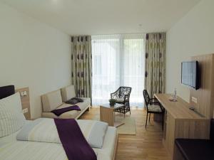 uma sala de estar com uma cama, uma secretária e uma televisão em Hotel Anker em Bodman-Ludwigshafen