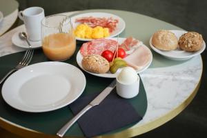a table with plates of food and a glass of orange juice at TheROOMS by TheFLOOR Collection in Milan +55 photos
