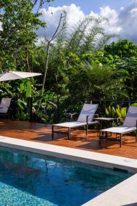 a deck with two chairs and a swimming pool at Arenal Manoa Hot Springs Resort in Fortuna
