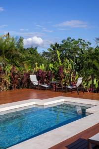 a pool with chairs and a table on a deck at Arenal Manoa Hot Springs Resort in Fortuna