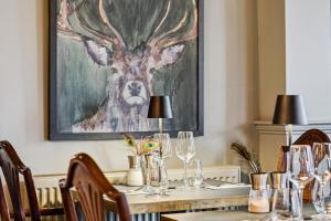 a dining room with a table with glasses and a painting at Flower Pot Hotel in Henley on Thames
