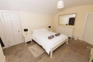 a bedroom with a white bed and a mirror at Principal Keeper's Cottage at Sumburgh Lighthouse, Shetland Islands in Sumburgh