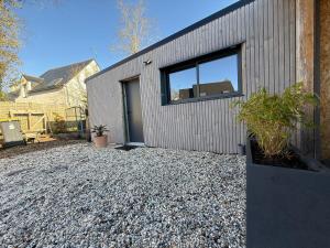 a gray house with a window on a gravel driveway at Le Petit Rhuys-parking-wifi in Surzur
