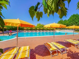 a swimming pool with yellow umbrellas and lounge chairs at Fruit Village Tropea Baia della Rocchetta Soft all Inclusive in Conidoni