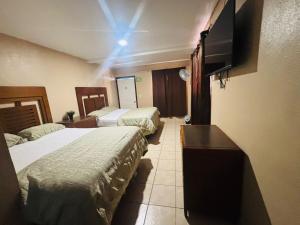 a hotel room with two beds and a flat screen tv at Hotel Del Bosque in Tijuana