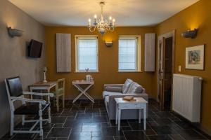 a living room with a couch and a chair at B&B Kamer en Aambeeld in Zoutleeuw