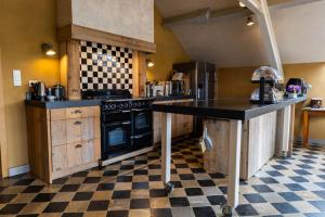 a kitchen with a black stove and a checkered floor at B&B Kamer en Aambeeld in Zoutleeuw