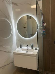 a bathroom with a white sink and a mirror at Apartman MAD Bjelasnica in Bjelašnica +12 photos