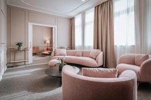 a living room with pink couches and a table at Palatinus Grand Hotel in Pécs