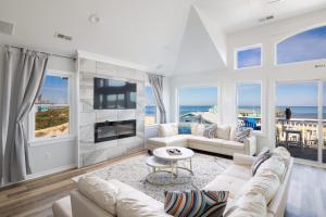 a living room with white furniture and a view of the ocean at Nags Head Oceanfront Private Beach Access & Pool in Nags Head